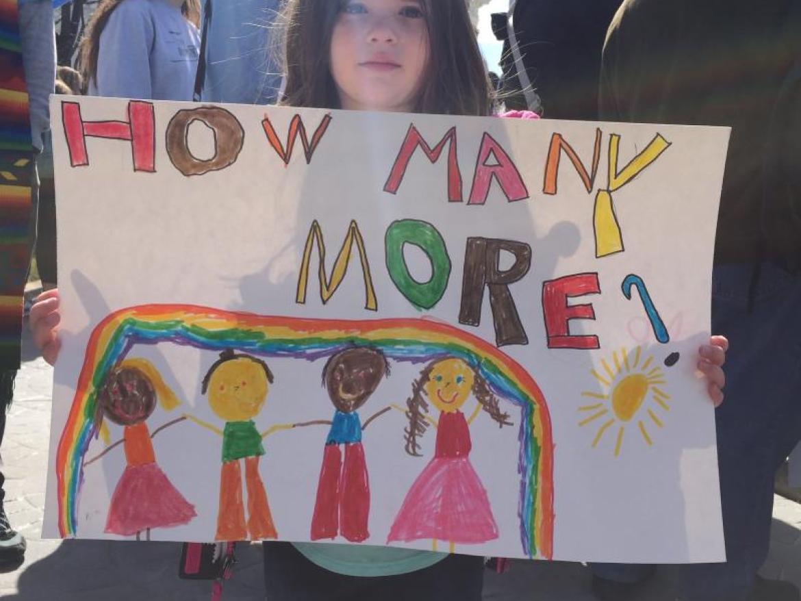 Young girl with a sign reading 'How Many More'